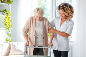 Nurse helps elderly woman with walker