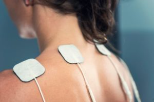 Woman Using TENS Electrodes For Pain Relief