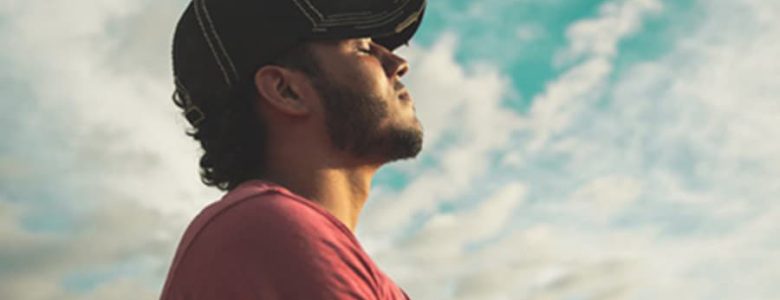 Man with hat under clouds experiencing serenity