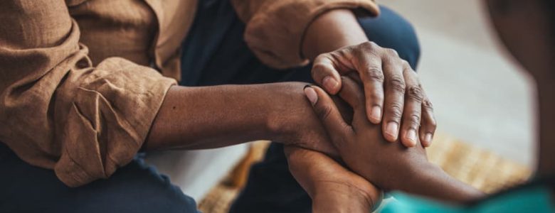 Home caregiver holding patient’s hands